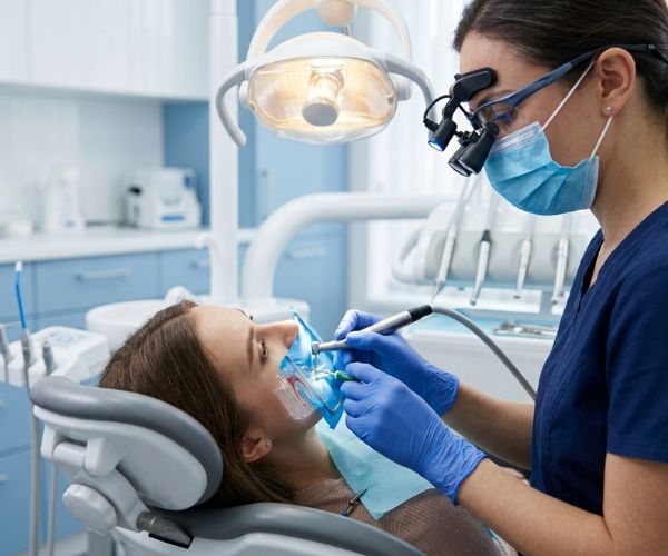 Expert endodontist performing procedure with modern magnifying loupes and precision instruments.